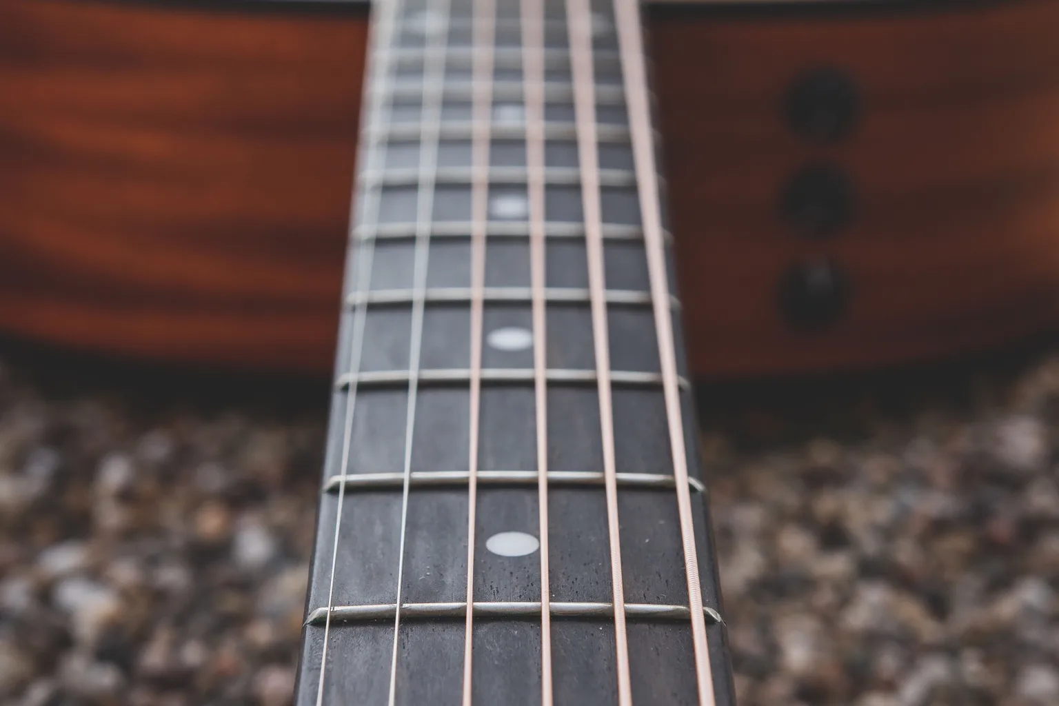 A close-up of an acoustic guitar’s strings and fretboard.